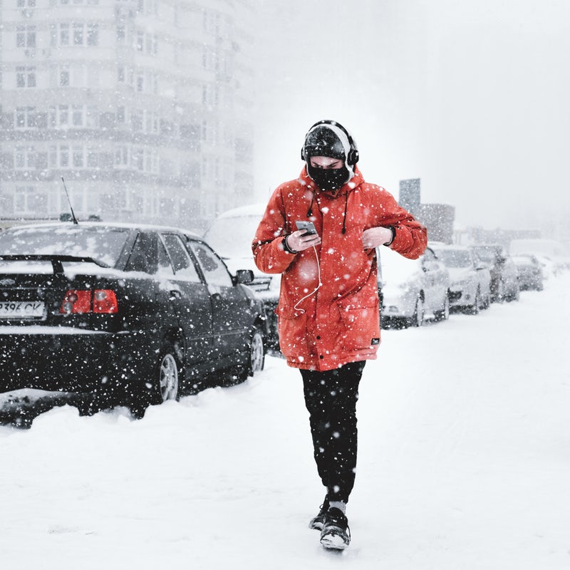 Ragazzo che cammina sotto la neve ascoltando musica